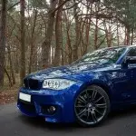 1M išvaizdos Priekinis Bamperis skirtas BMW E81 / E82 / E87 / E88, be PDC, be apiplovimų angų