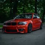 1M išvaizdos Priekinis Bamperis skirtas BMW E81 / E82 / E87 / E88, be PDC, be apiplovimų angų
